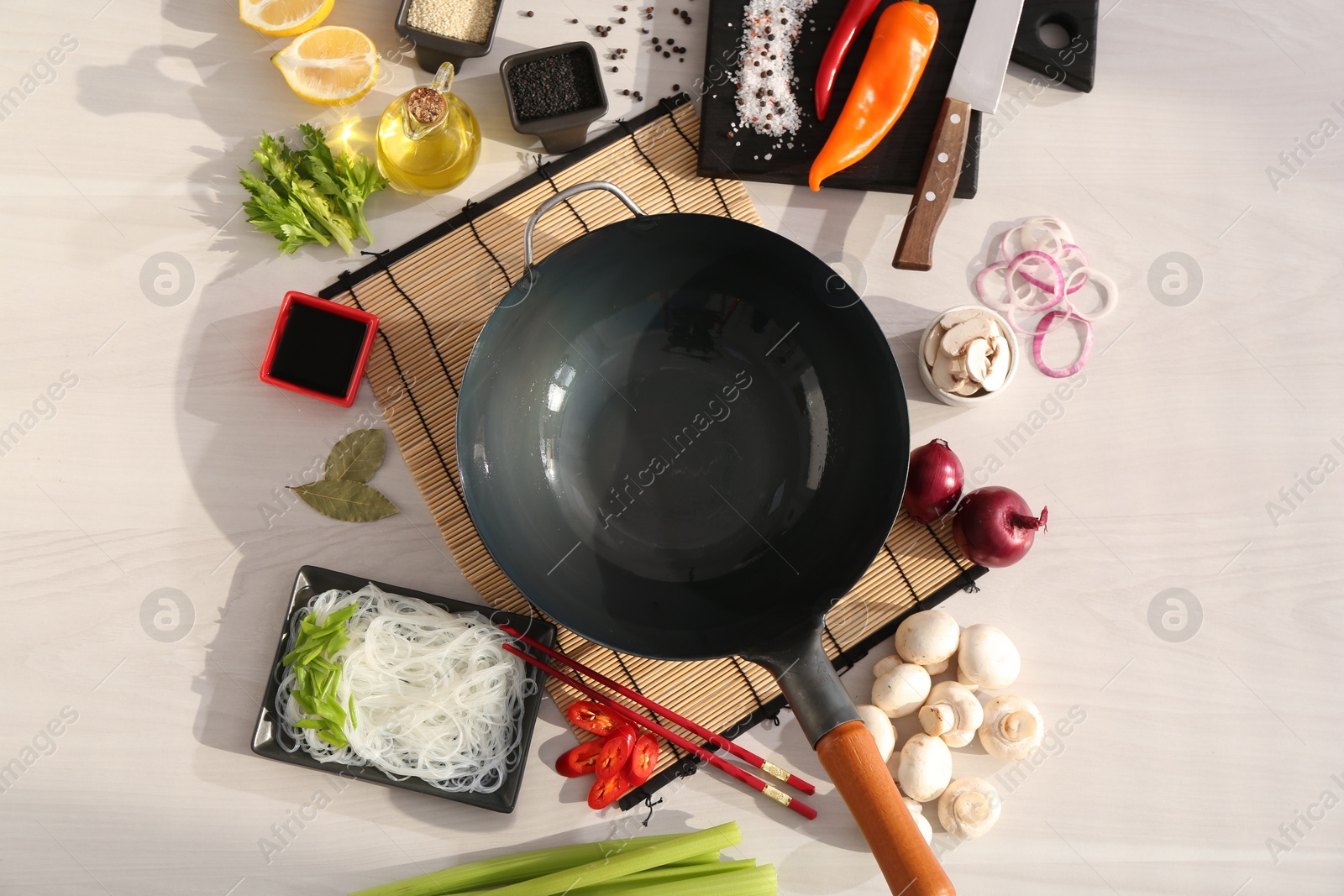 Photo of Wok, chopsticks and different products on white wooden table, flat lay