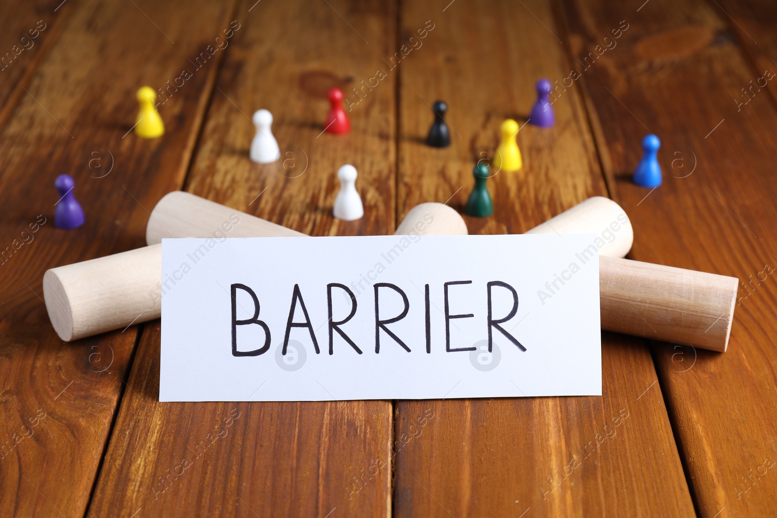 Photo of Wooden blocks as barrier blocking way for small human figures and paper note on table, closeup. Development through obstacles overcoming