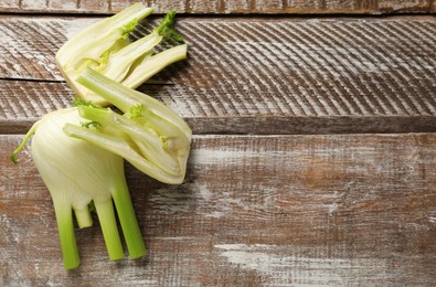 Photo of Whole and cut fennel bulbs on wooden table, top view. Space for text