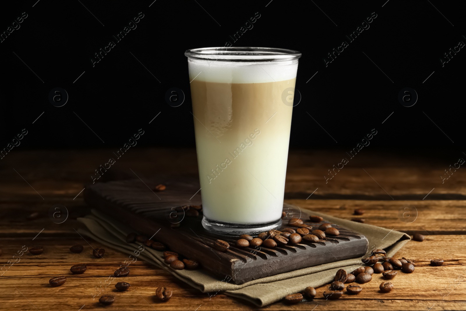 Photo of Delicious latte macchiato and coffee beans on wooden table