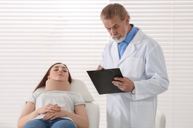 Photo of Orthopedist examining patient with injured neck in clinic