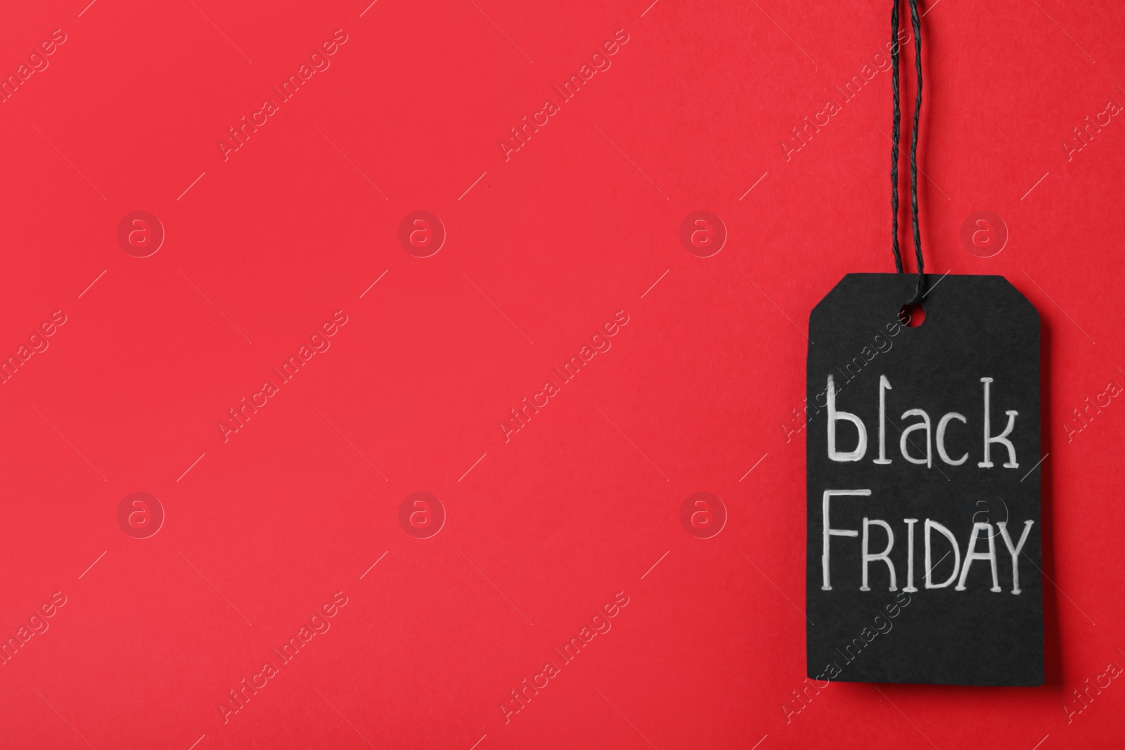 Photo of Black Friday tag on red background, space for text