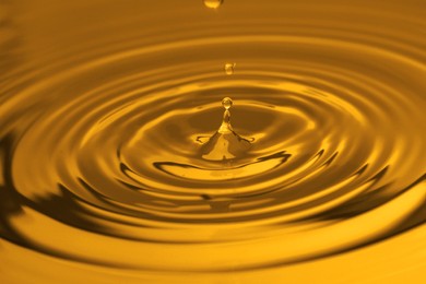Splash of golden oily liquid with drops as background, closeup