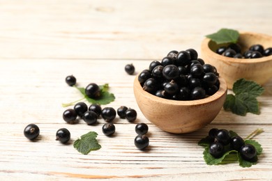 Photo of Ripe blackcurrants and leaves on light wooden table. Space for text