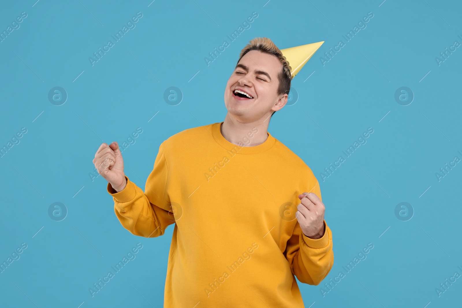 Photo of Young man with party hat on light blue background