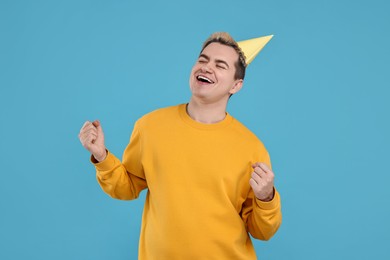 Photo of Young man with party hat on light blue background