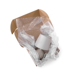 Photo of Lamp with bubble wrap in cardboard box isolated on white, above view