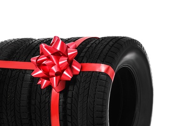Photo of Winter tires with red ribbon on white background, closeup