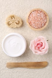 Photo of Flat lay composition with moisturizing cream in open jar and other body care products on light textured table