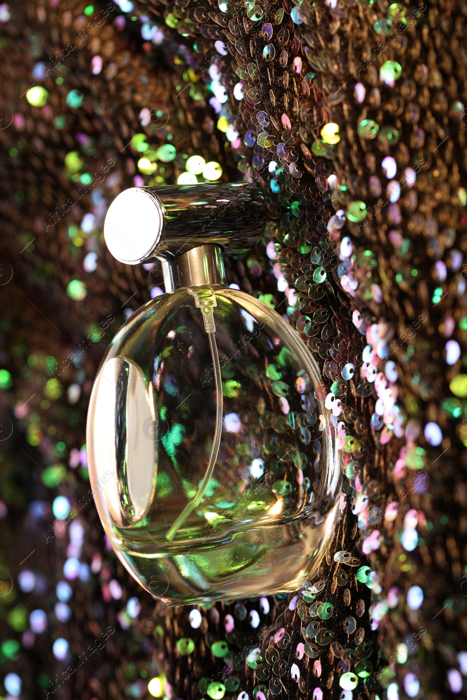 Photo of Luxury perfume in bottle on fabric with colorful sequins