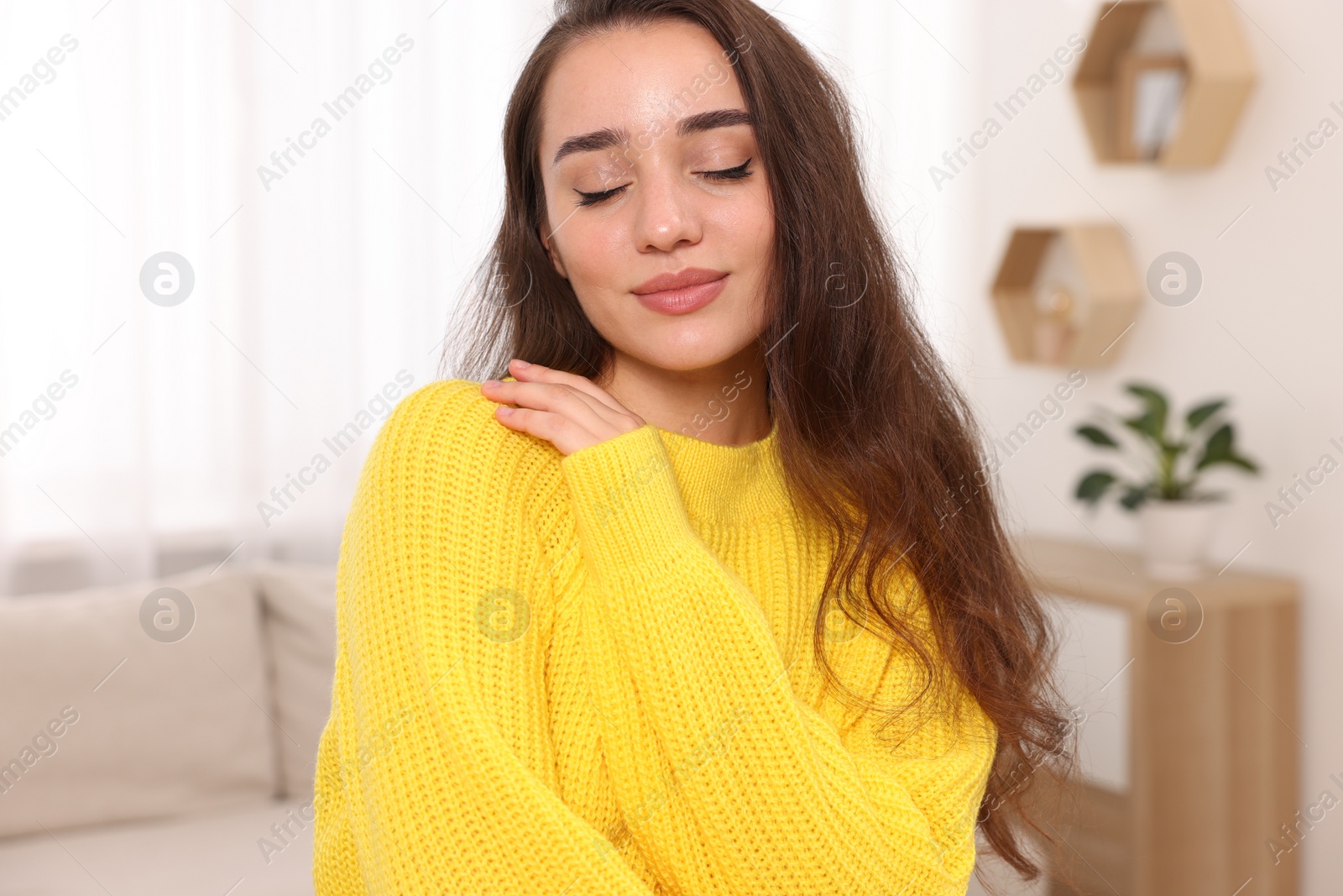 Photo of Beautiful young woman in stylish warm sweater at home