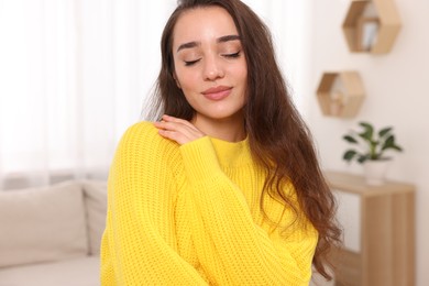 Photo of Beautiful young woman in stylish warm sweater at home