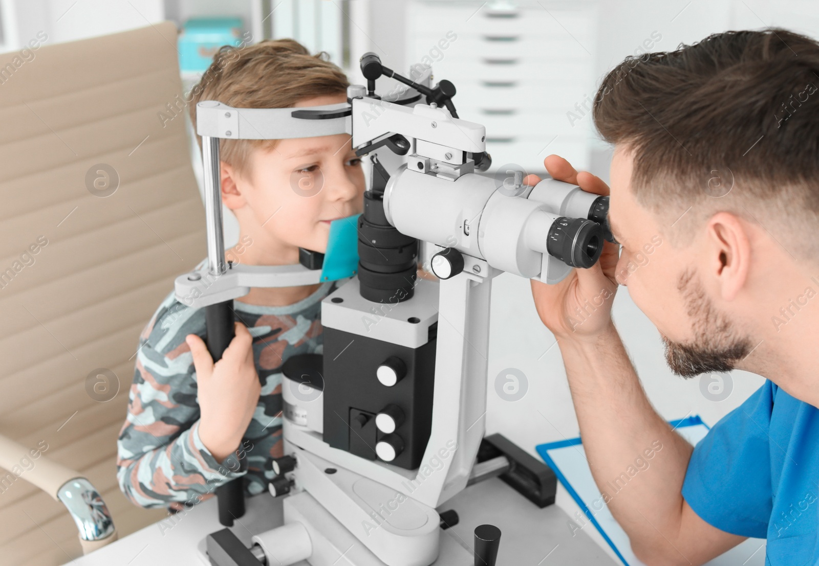 Photo of Ophthalmologist examining little boy in clinic
