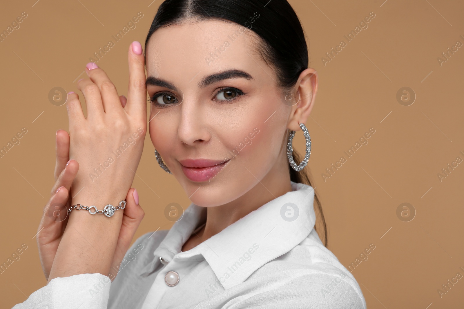 Photo of Young woman with elegant jewelry on beige background