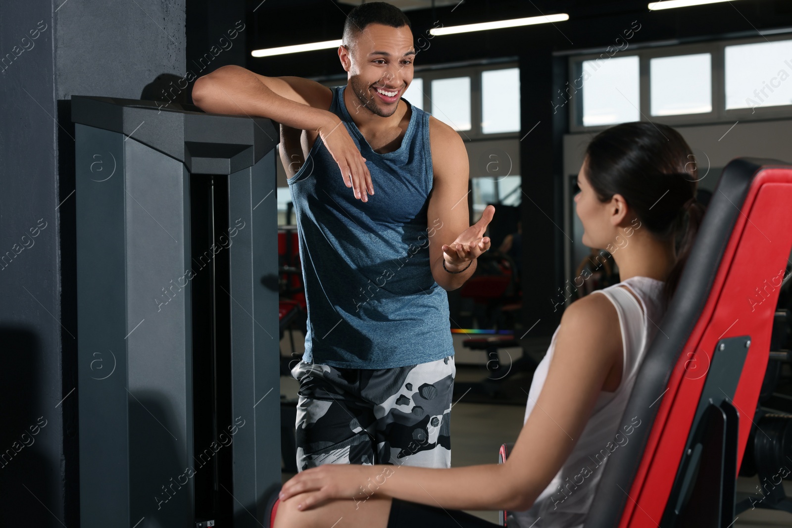 Photo of Happy trainer having discussion with woman in gym