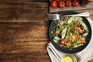 Photo of Delicious salad with lentils and vegetables served on wooden table, flat lay. Space for text