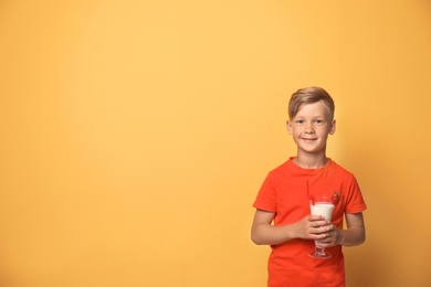 Little boy with glass of milk shake on color background