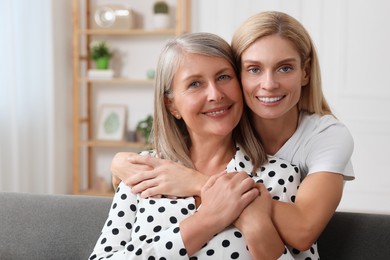 Happy mature mother and her daughter hugging at home