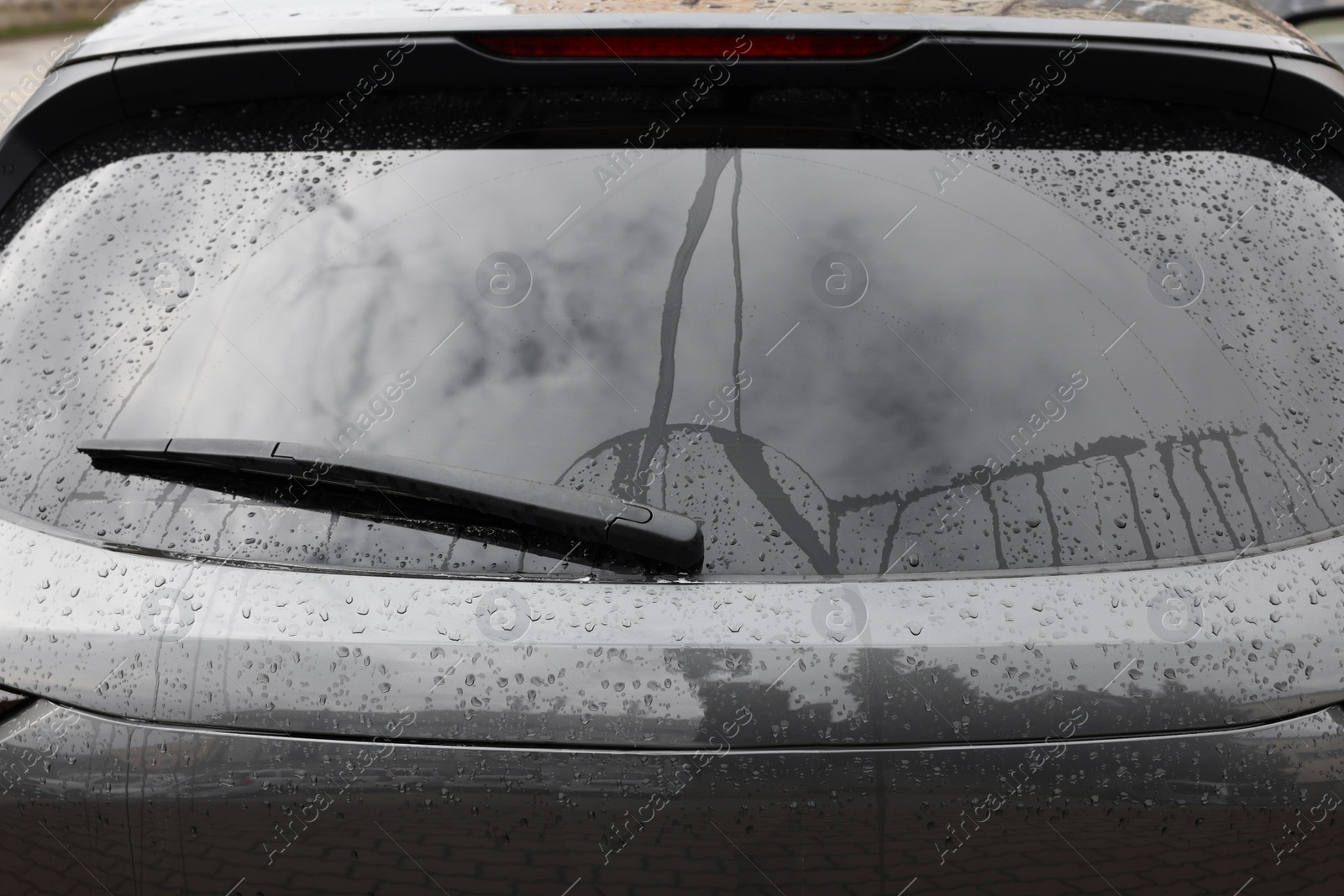 Photo of Car wiper cleaning water drops from rear windshield glass, closeup