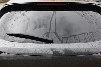 Photo of Car wiper cleaning water drops from rear windshield glass, closeup