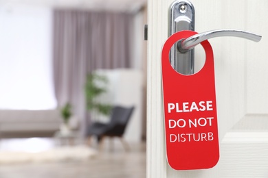 Photo of Open door with sign PLEASE DO NOT DISTURB on handle at hotel, space for text