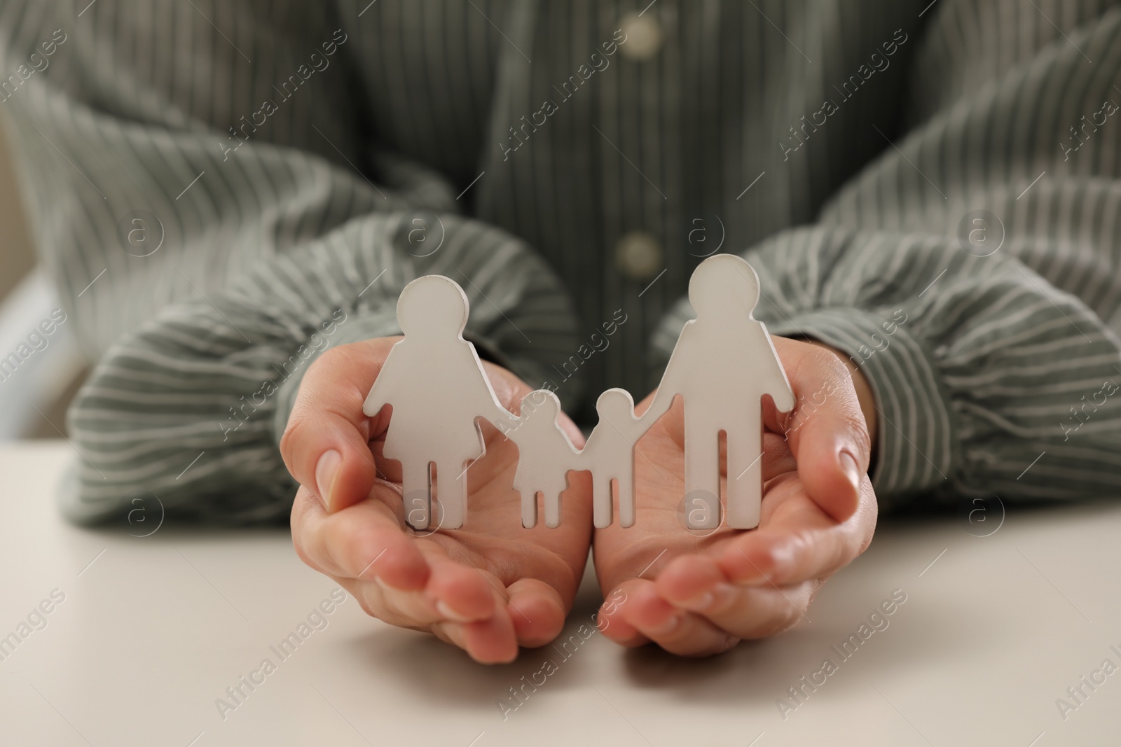 Photo of Woman holding figure of family at white table, closeup