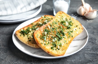 Photo of Plate with delicious homemade garlic bread on table