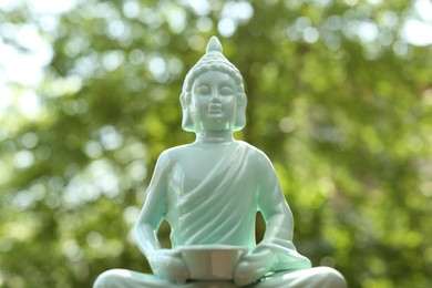 Photo of Beautiful ceramic Buddha sculpture on blurred background, closeup