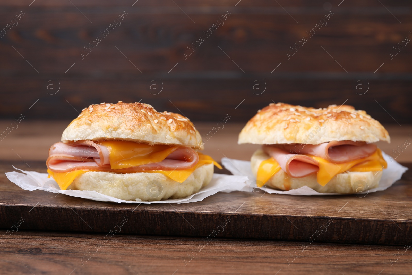 Delicious bagels with ham and cheese on wooden table Photo of Delicious bagels with ham and cheese on wooden table