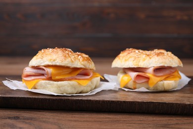 Photo of Delicious bagels with ham and cheese on wooden table