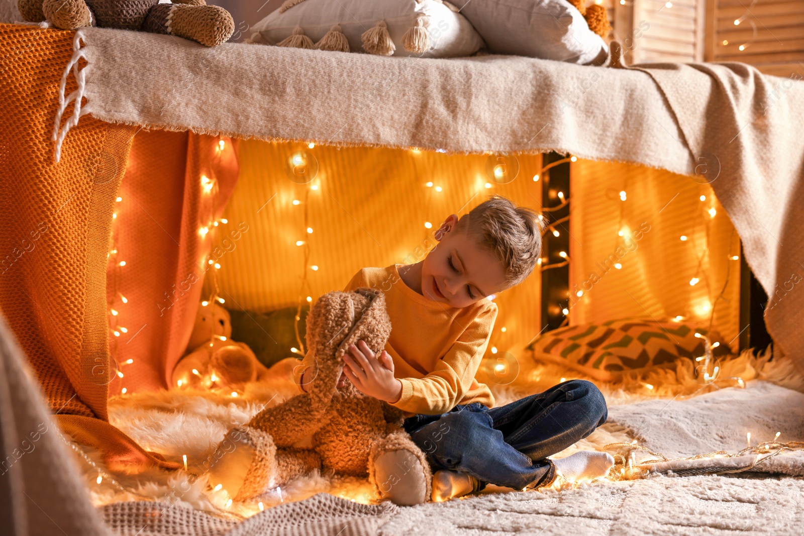 Photo of Boy playing with toy bunny in play tent at home