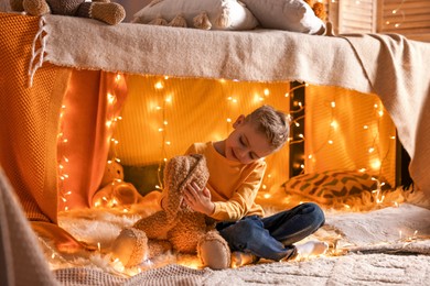 Photo of Boy playing with toy bunny in play tent at home