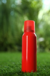 Bottle of insect repellent spray on green grass