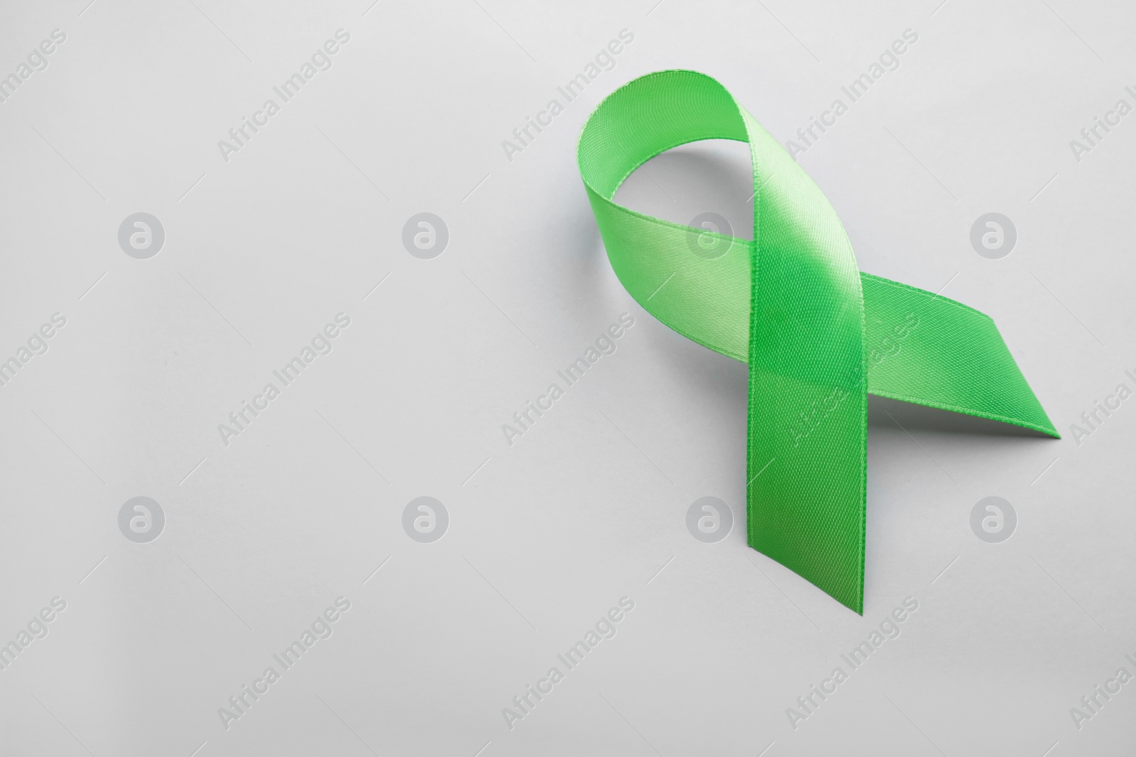 Photo of World Mental Health Day. Green ribbon on color background, top view with space for text