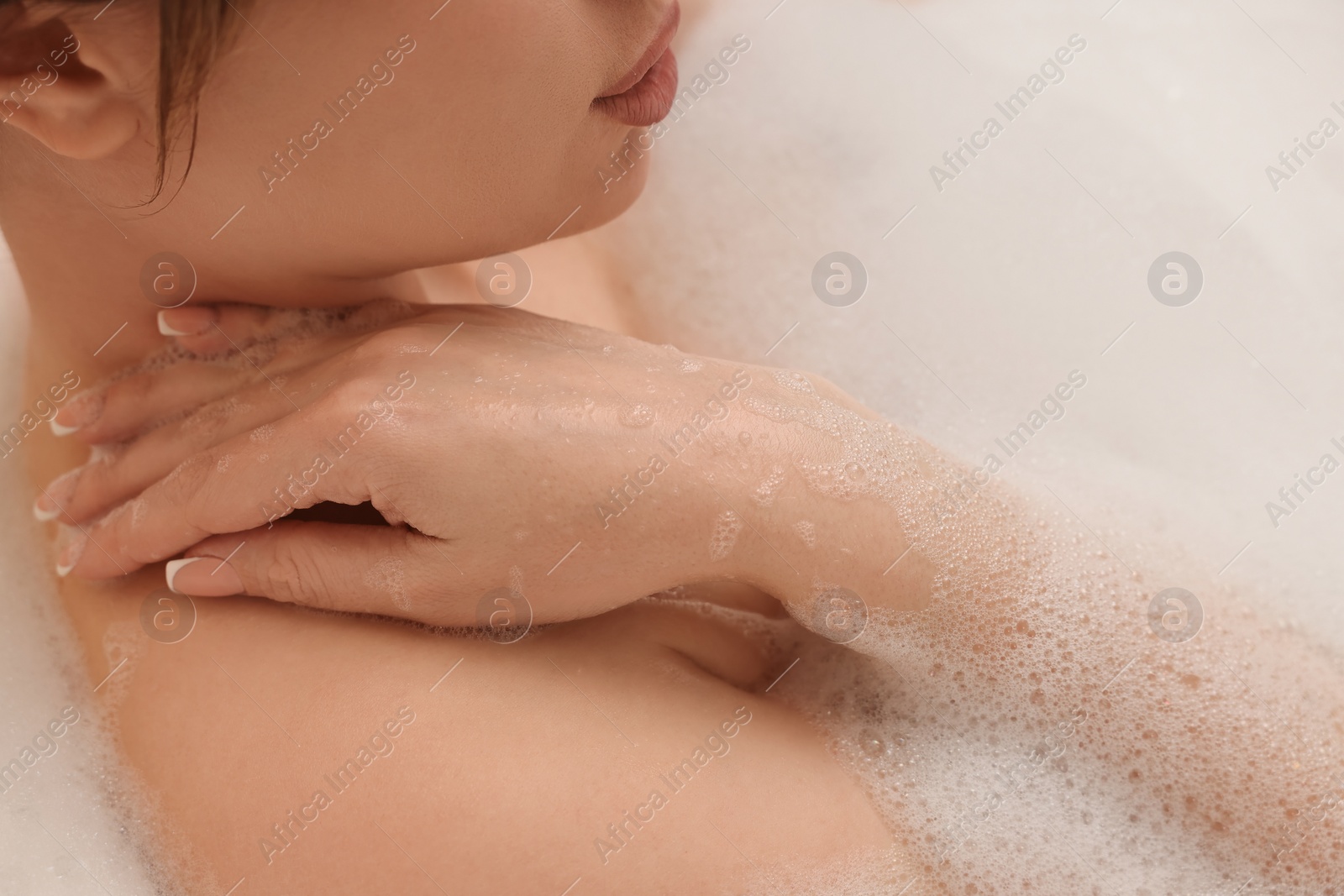 Photo of Woman taking bath with foam in tub, closeup