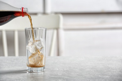 Photo of Pouring cola from bottle into glass on table. Space for text