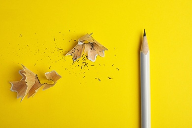 Photo of Pencil and shavings on yellow background, flat lay