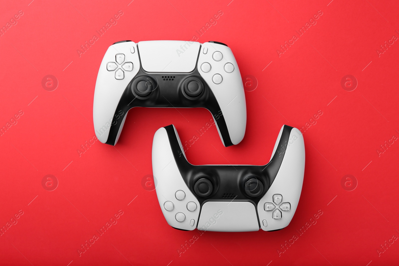 Photo of Wireless game controllers on red background, flat lay