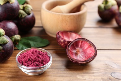 Photo of Purple mangosteen powder and fruits on wooden table