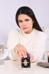 Soothsayer predicting future with tarot cards at table in room