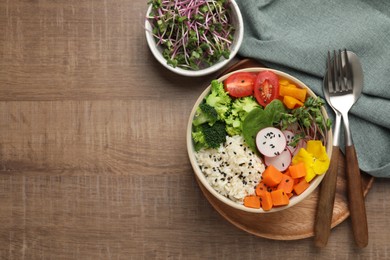 Photo of Bowl with many different vegetables and rice on wooden table, flat lay and space for text. Vegan diet