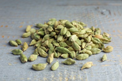 Photo of Pile of dry cardamom pods on grey wooden table