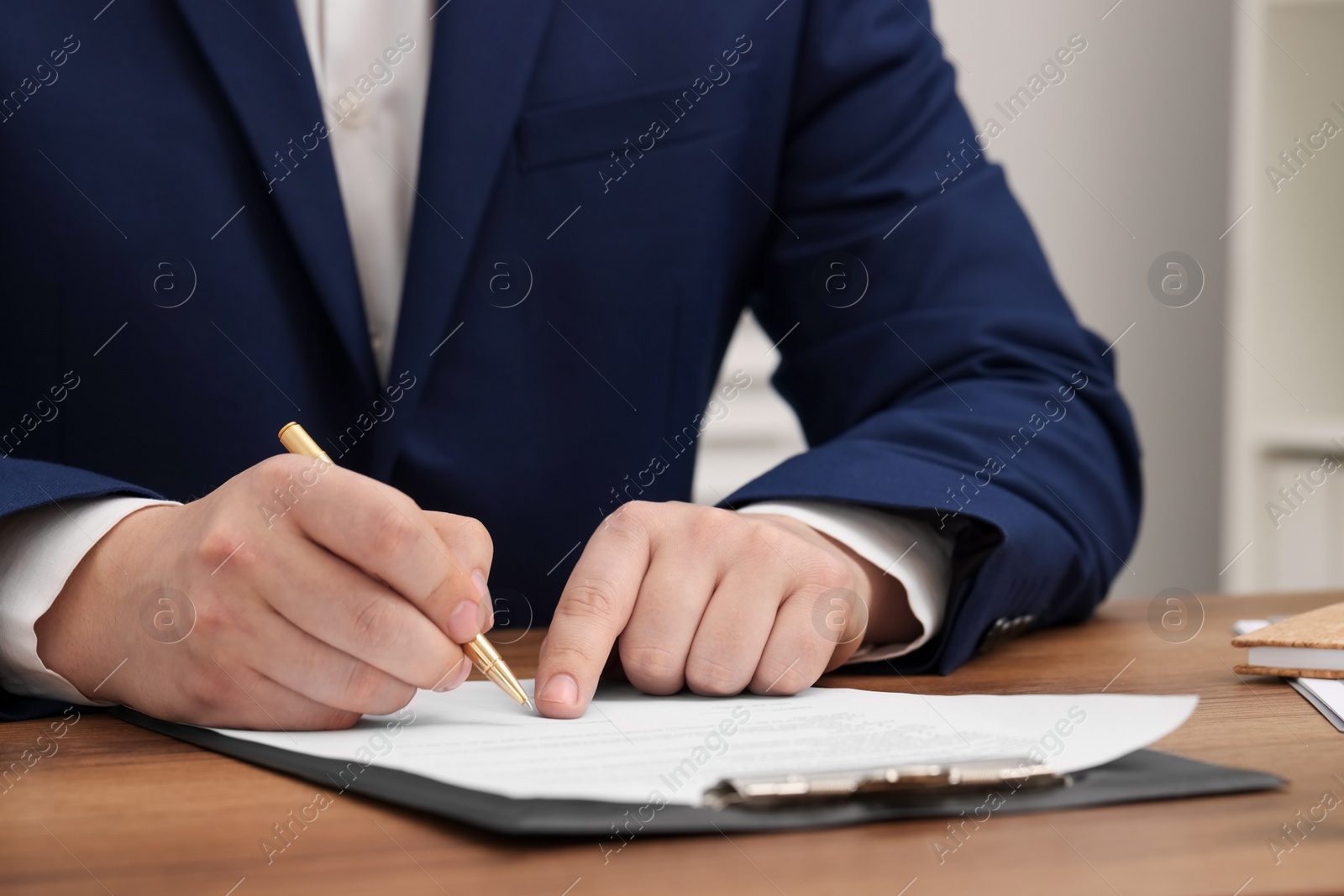 Photo of Man signing document at wooden table, closeup