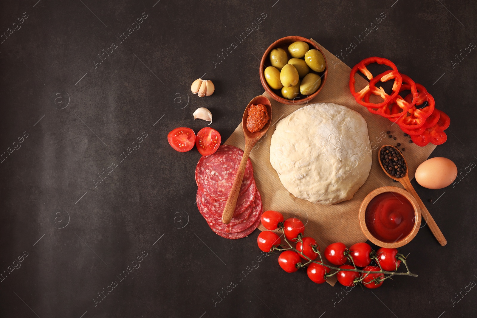 Photo of Pizza dough and products on dark table, flat lay. Space for text