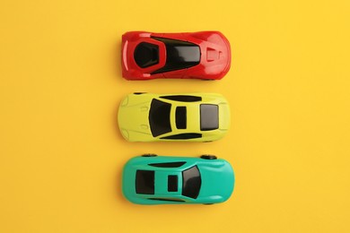 Photo of Different bright cars on yellow background, flat lay. Children`s toys