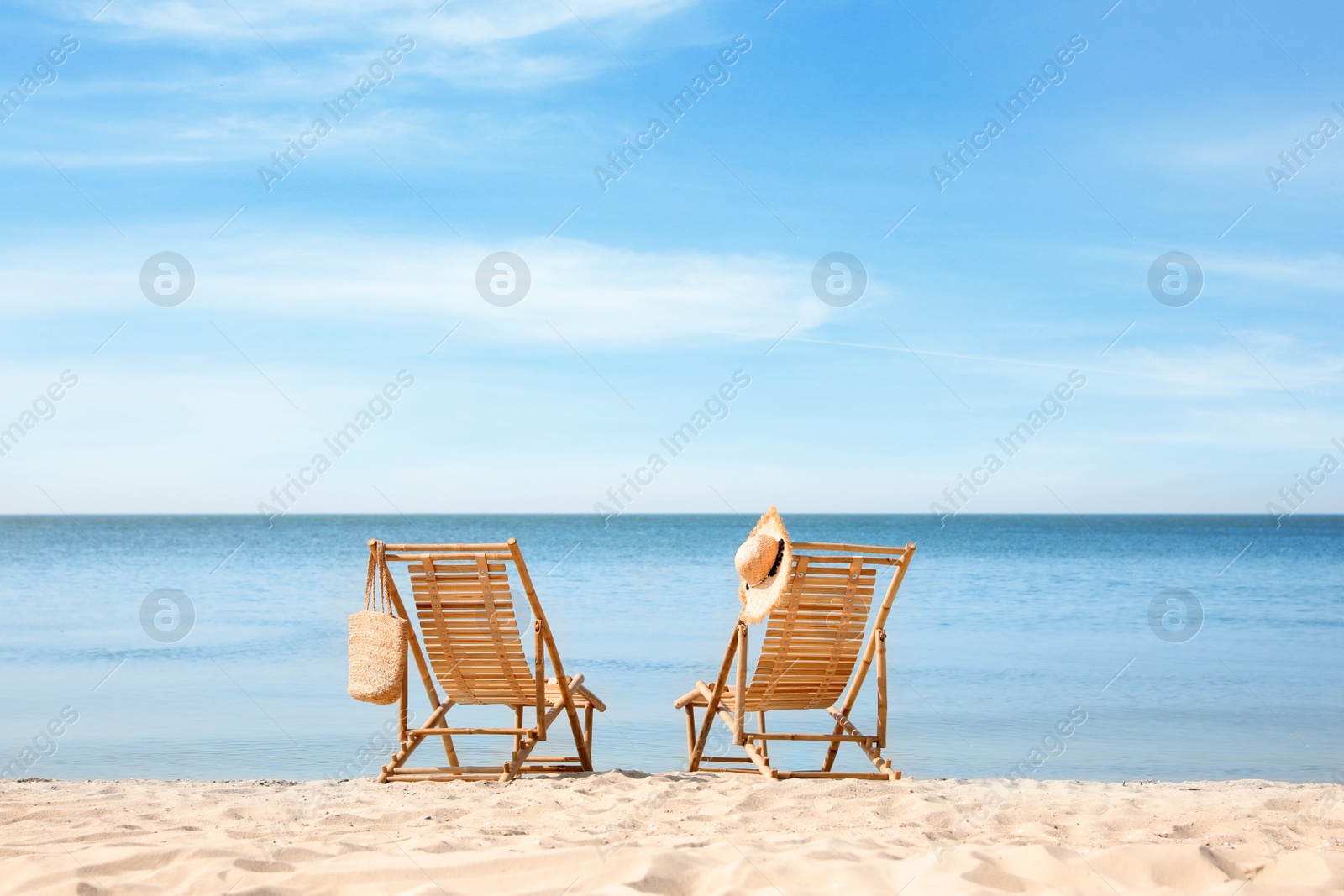 Photo of Wooden deck chairs on sandy beach near sea