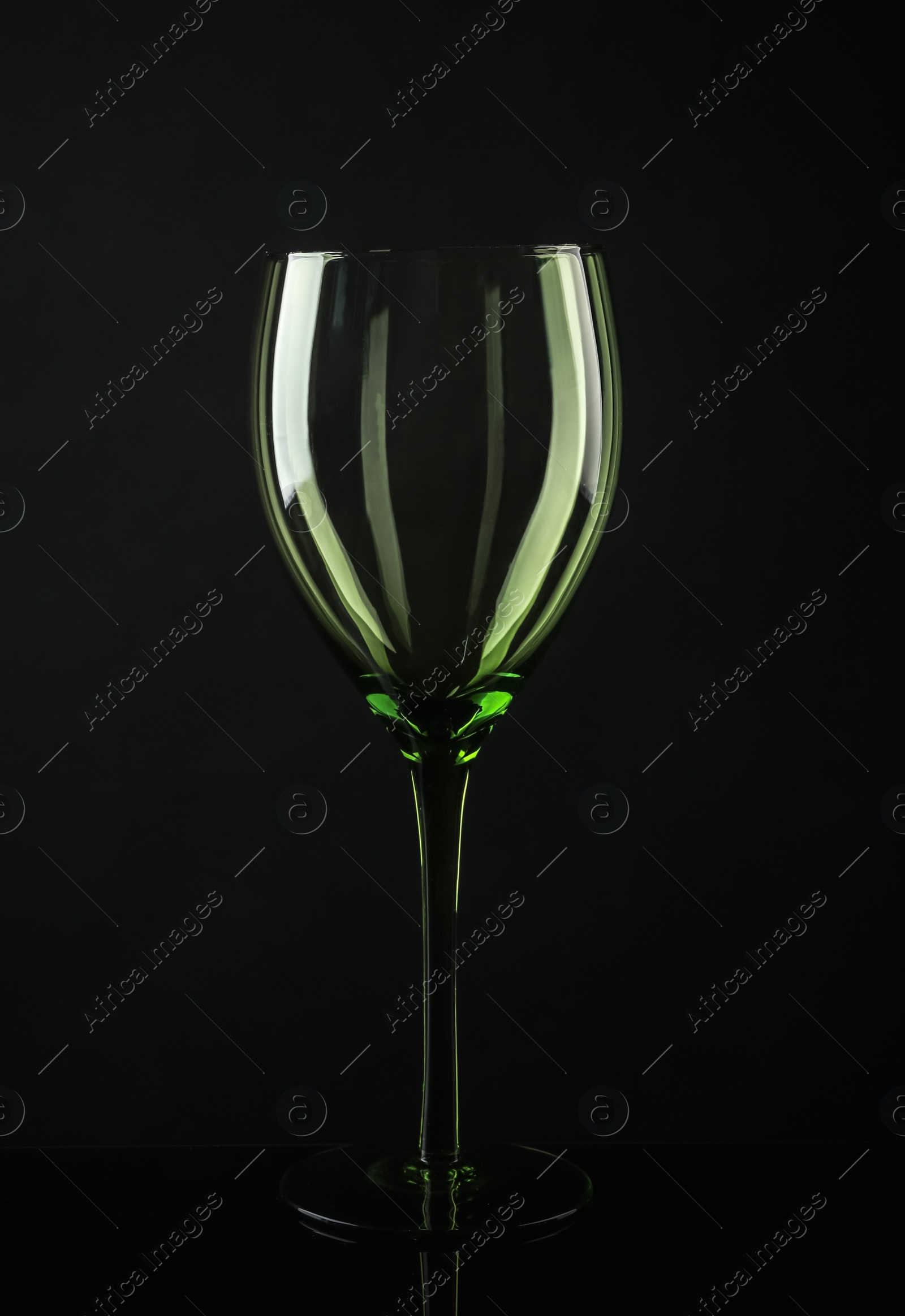 Photo of Elegant empty colorful wine glass on black background