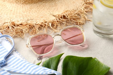 Photo of Stylish sunglasses and beach accessories on sand