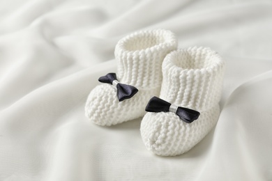 Handmade baby booties with bows on light plaid