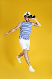 Photo of Emotional sailor with binoculars jumping on yellow background